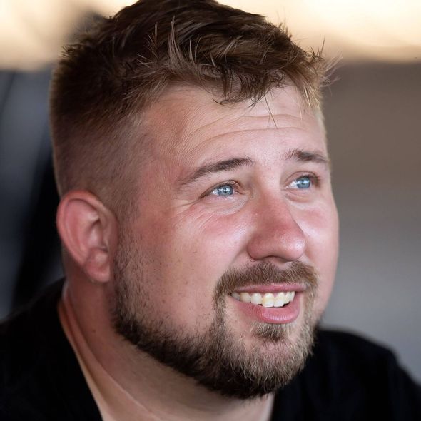 A man with a beard is smiling and wearing a black shirt