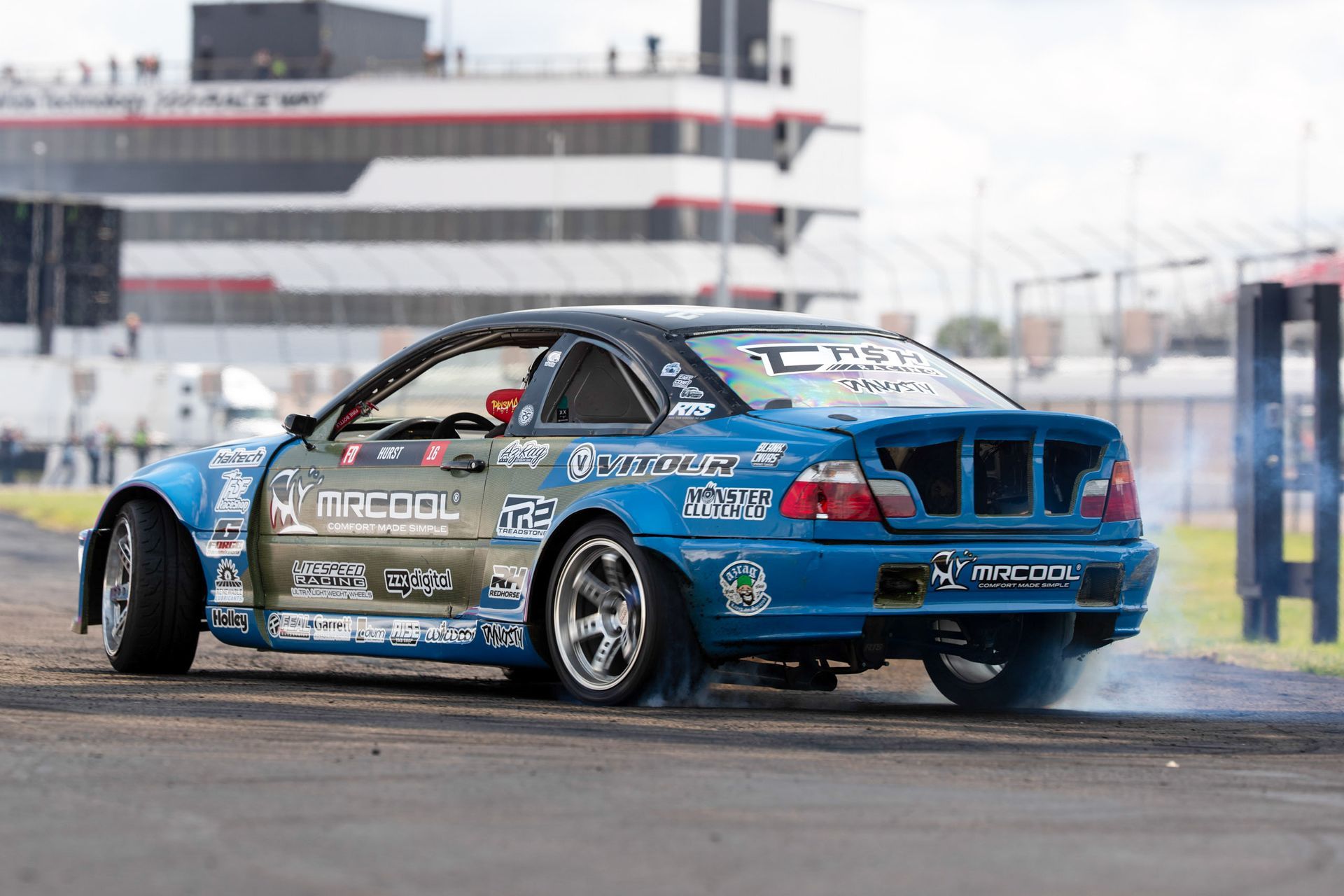 A blue car is drifting on a race track.