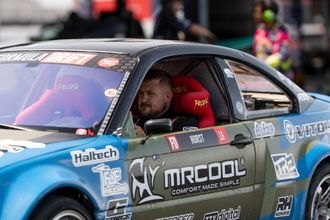 A man is sitting in the driver 's seat of a racing car.