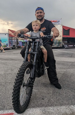 A man is sitting on a motorcycle with a child on his lap.