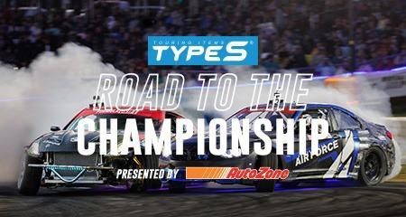 Two cars are racing on a track and the words `` road to the championship '' are above them.