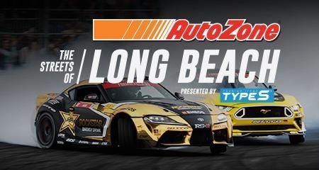 Two racing cars are driving down the streets of long beach.