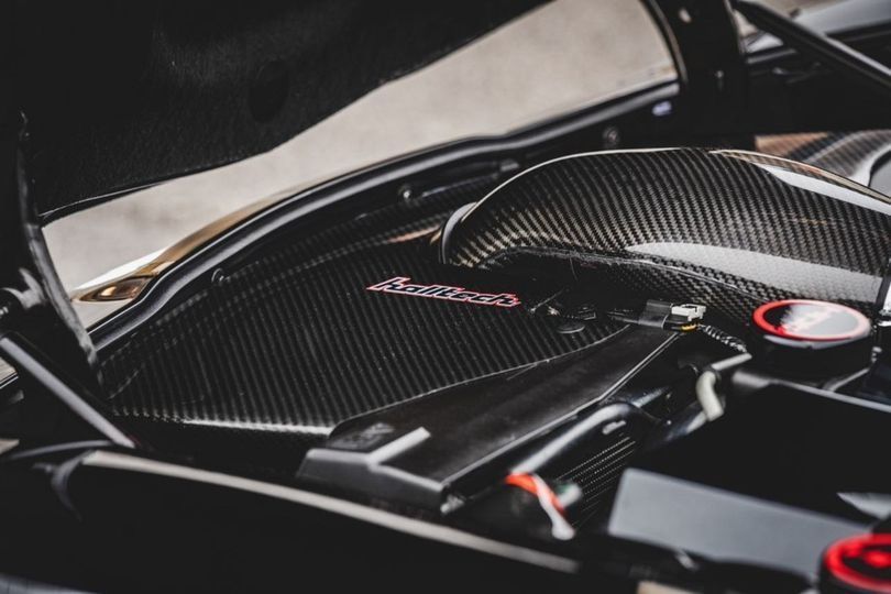 A close up of the engine of a black car with the hood open.
