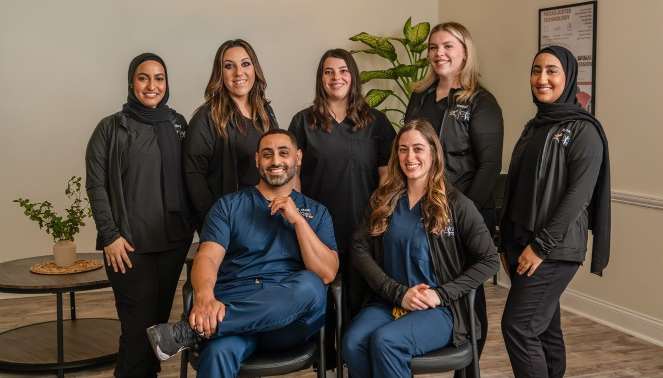 A group of seven medical professionals in scrubs and dark clothing posing for a team photo in a brightly lit office.