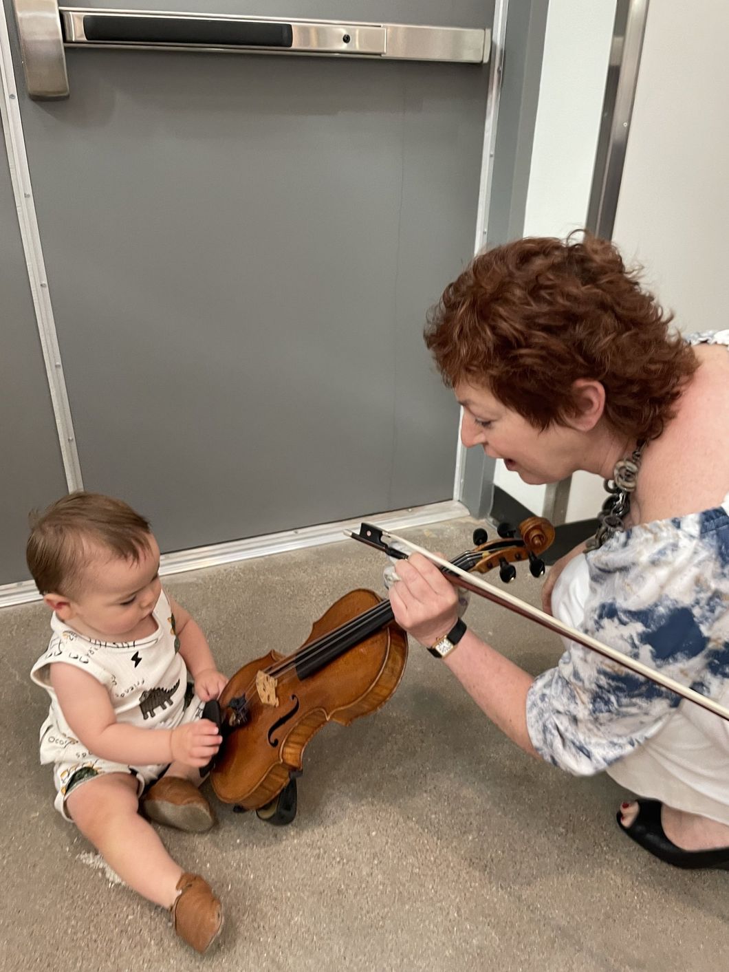 Jennifer Leshnower teaching a baby to play the violin.