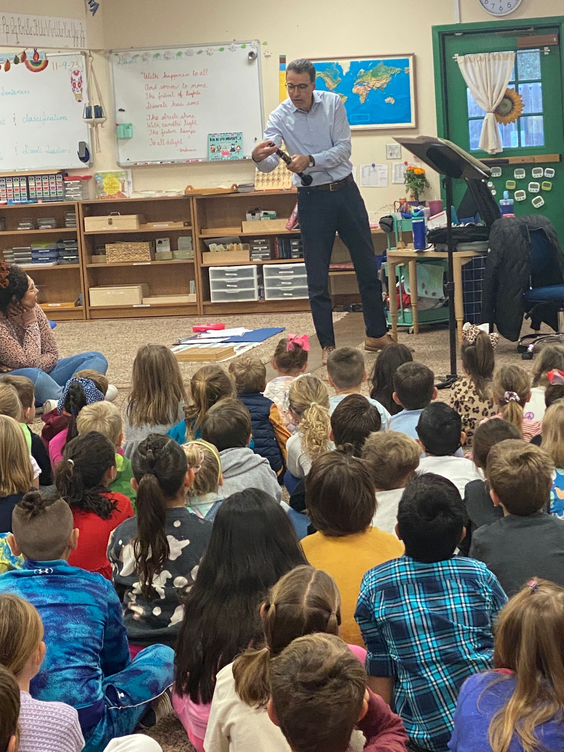 Man demonstrating to a group of children in a classroom.