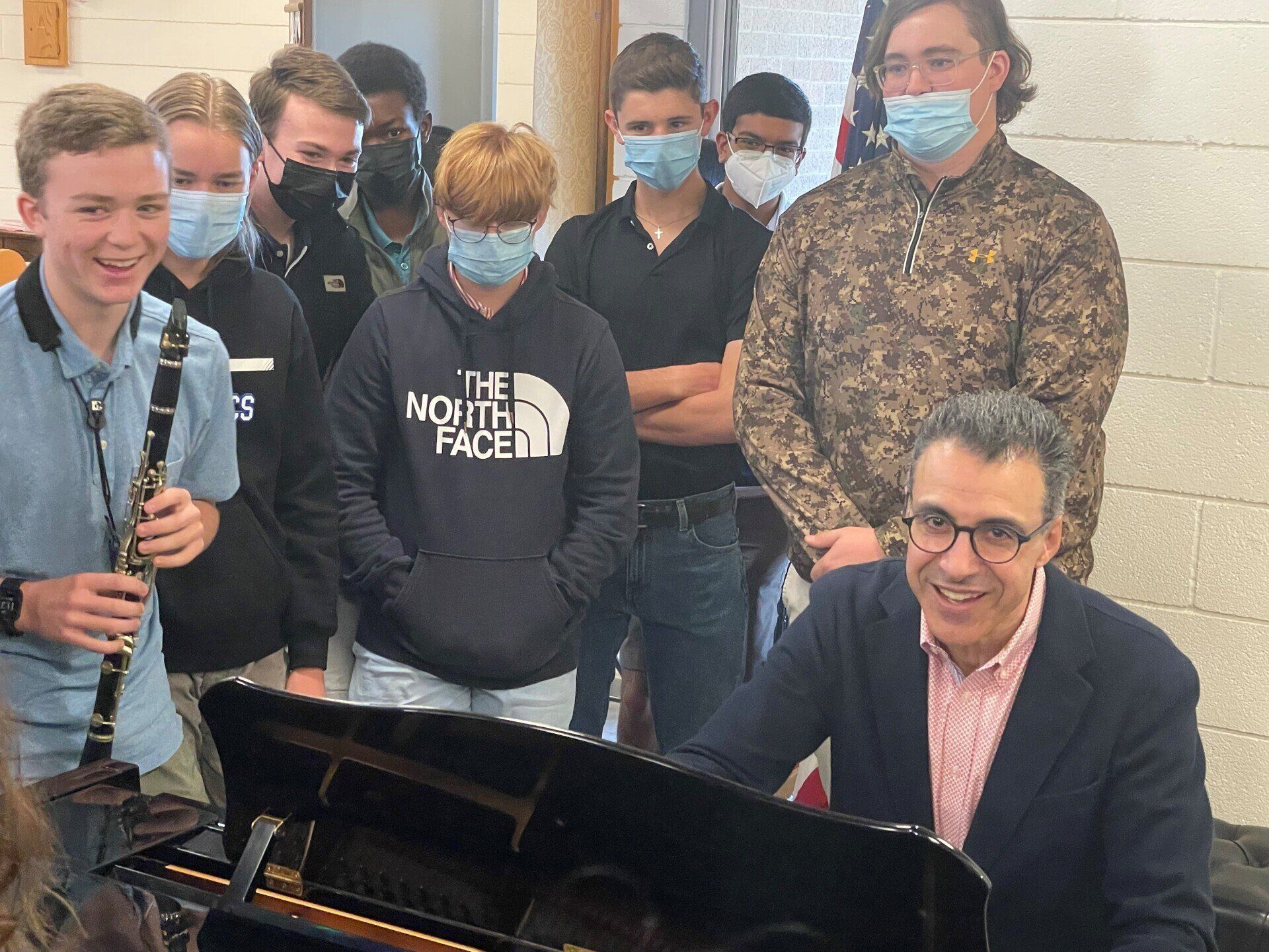 Oskar Espina-Ruiz playing piano, surrounded by masked students with a clarinet.