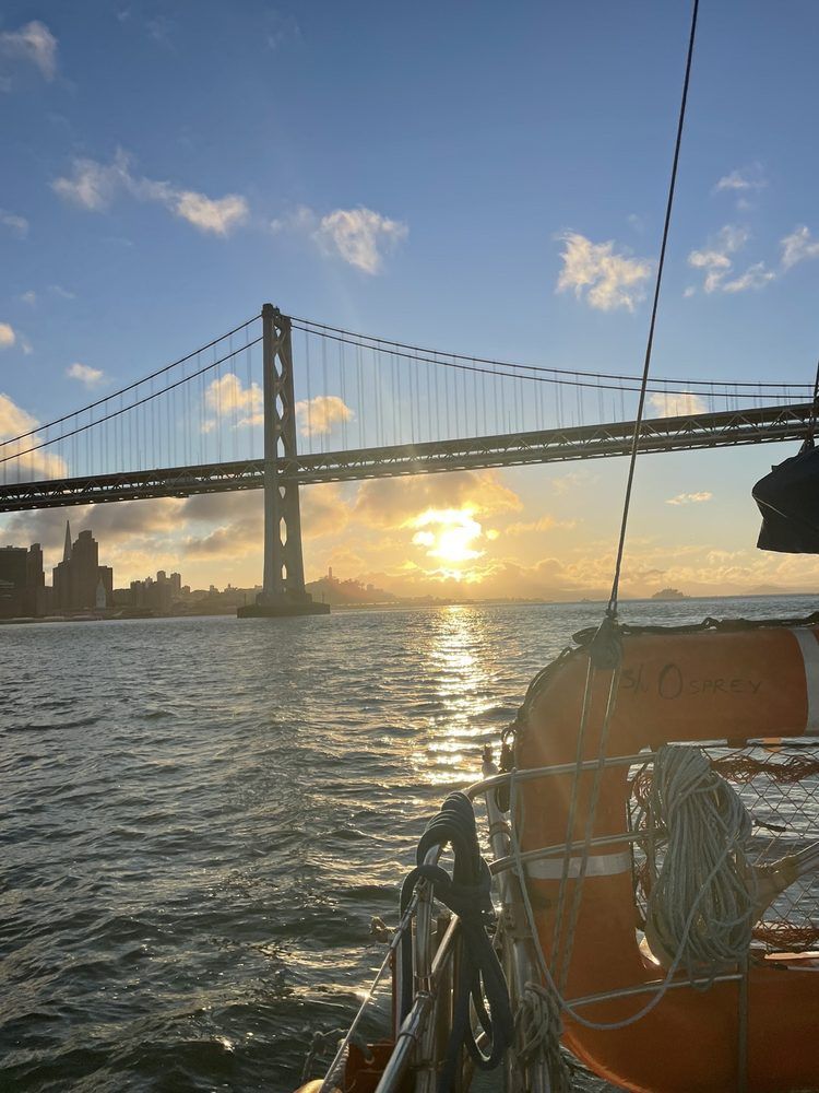 The sun behind the clouds with San Francisco and the Bay Bridge in the background.