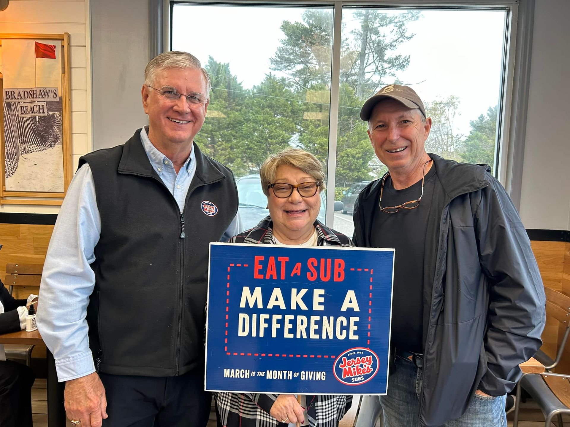 Three people pose inside a restaurant, holding a
