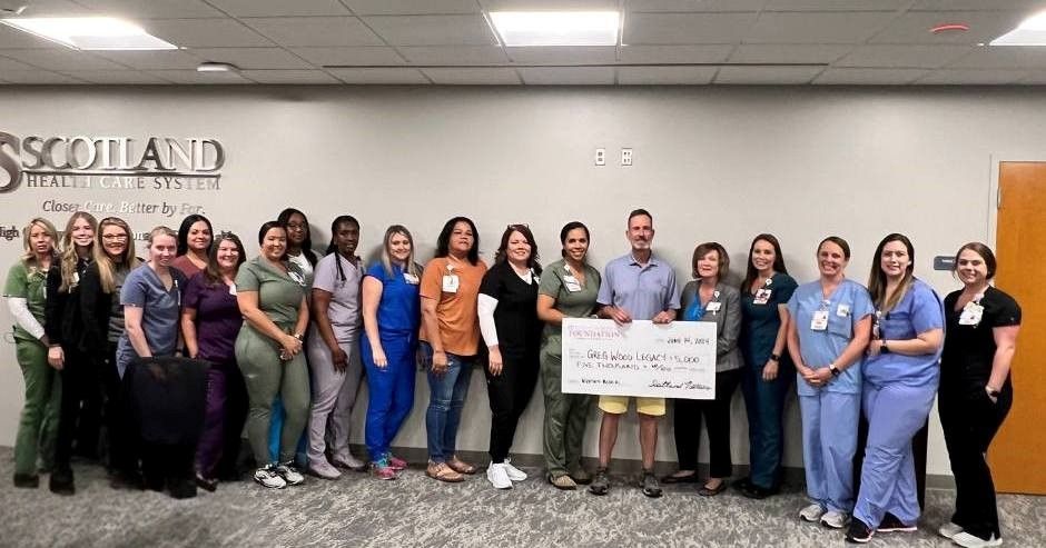 A group of people holding a large check inside a building with a