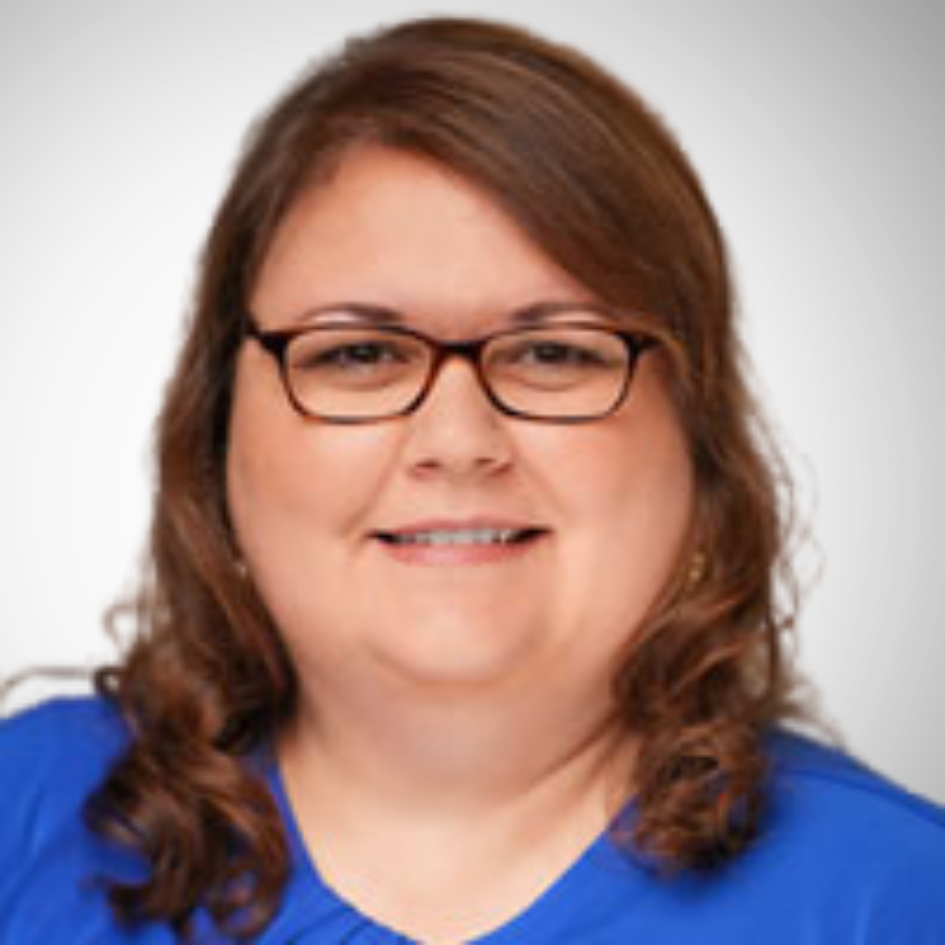 Woman with brown hair and glasses smiling in a blue shirt.