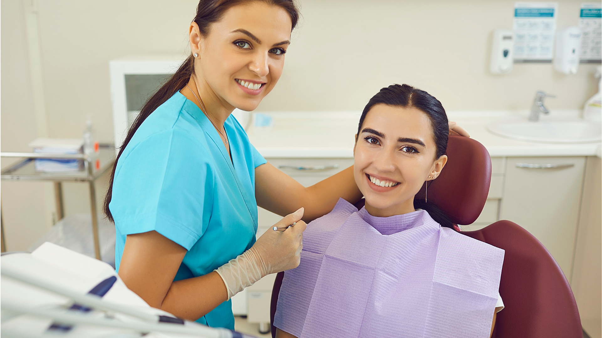 Dentist examining patient's teeth in a dental chair; medical tools visible.