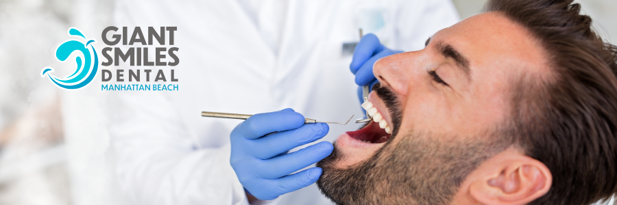 A dentist is holding a model of a person 's teeth with tweezers.