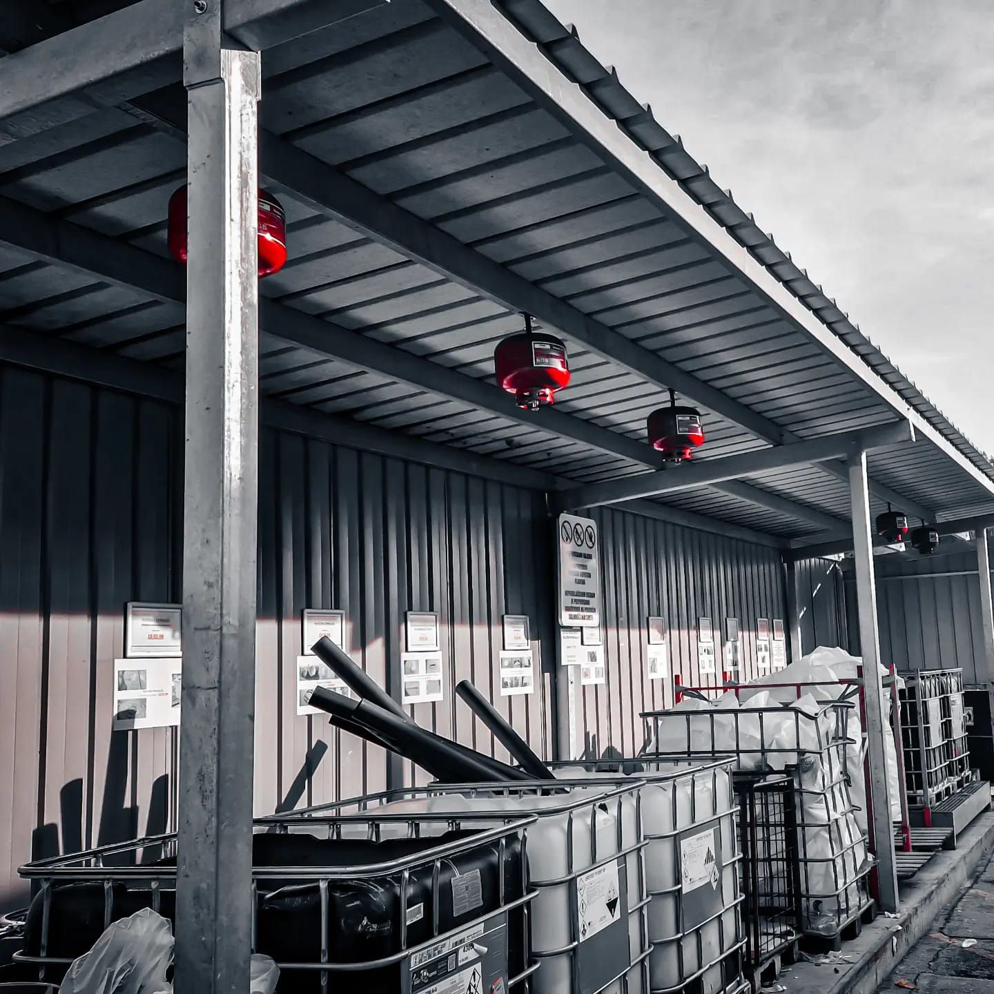 Een laadperron met metalen tanks, rode verlichting en wanden van golfplaat.
