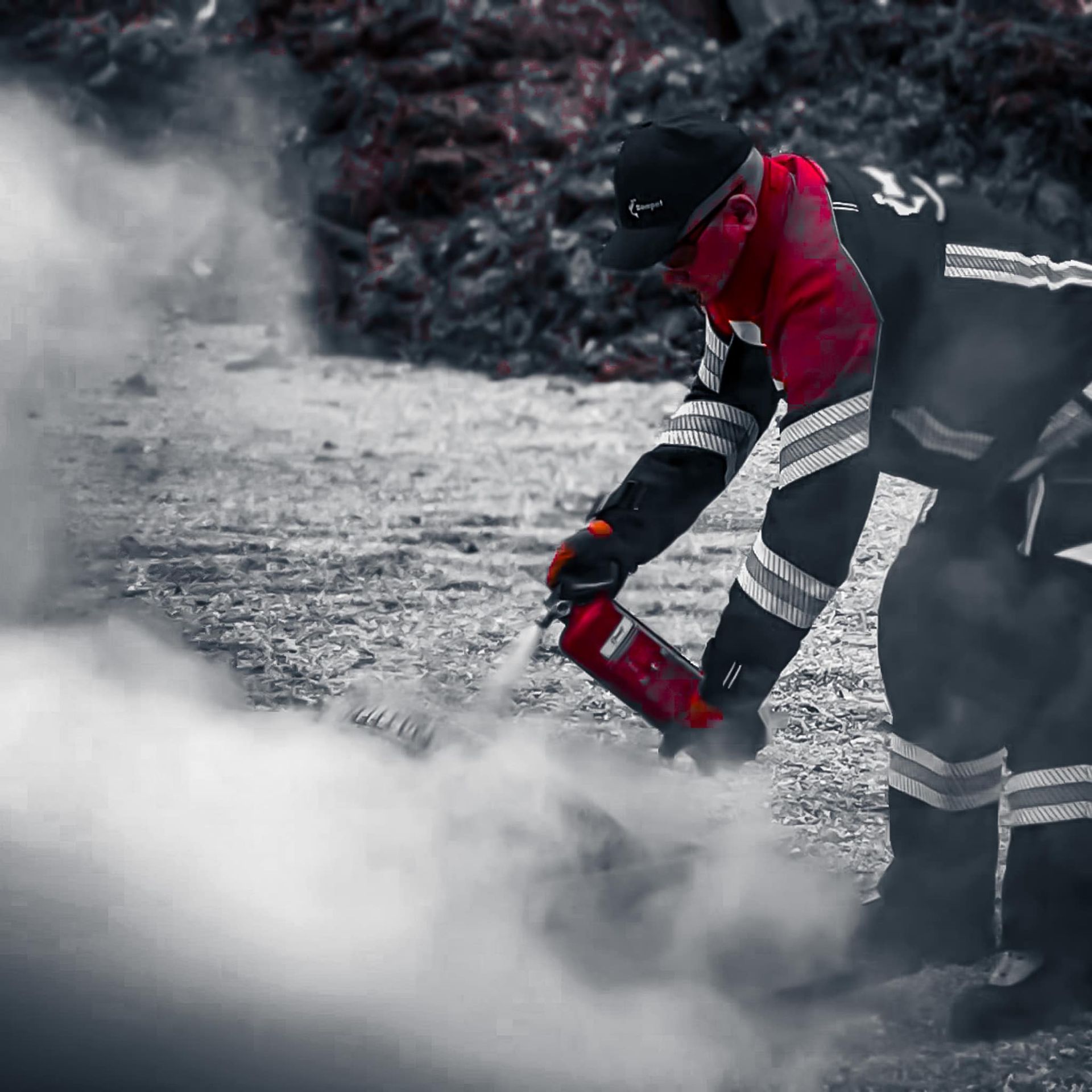 Brandweerman in rode jas, die een brandblusser gebruikt te midden van witte rook.