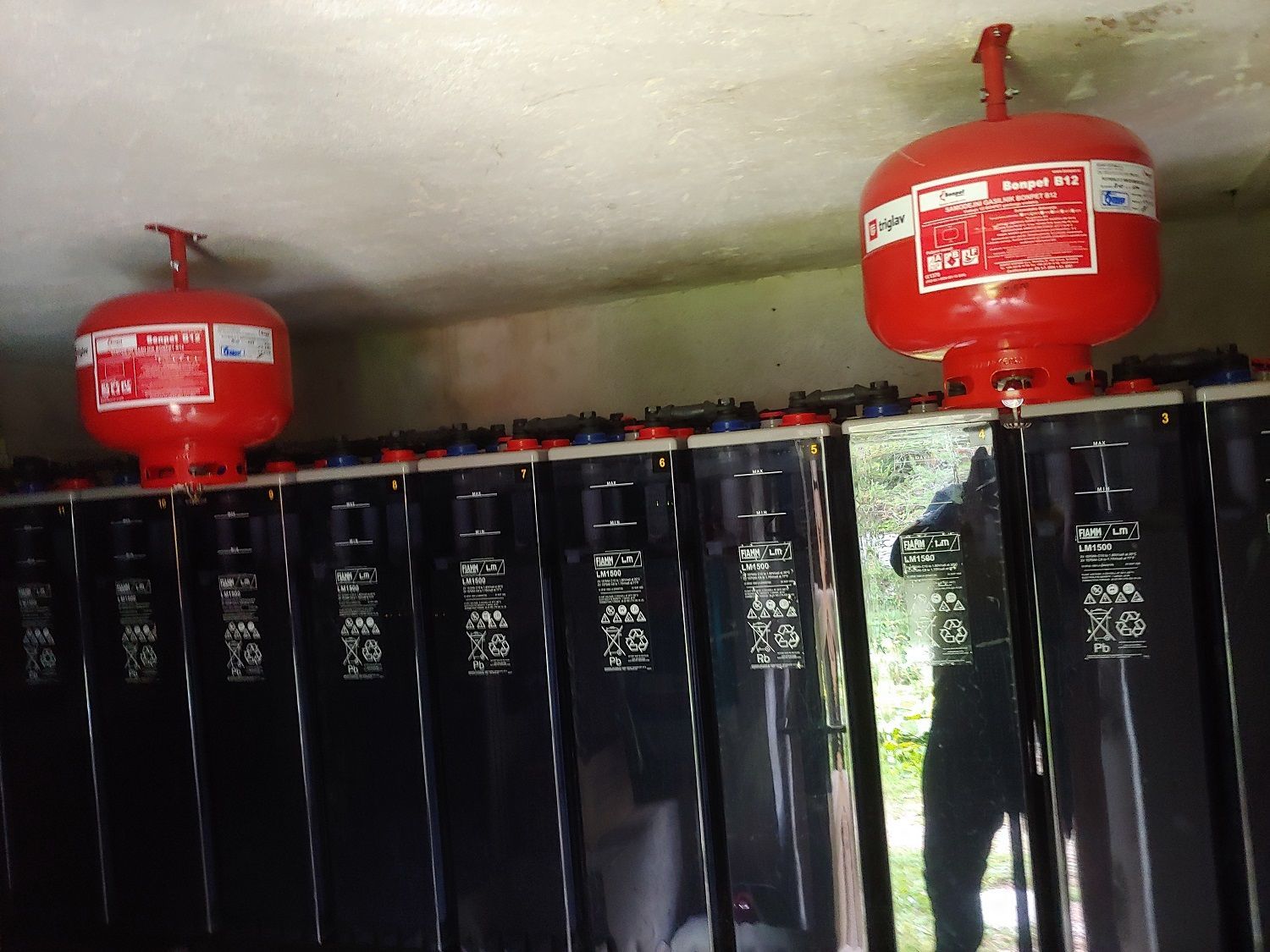 Rode brandblustanks gemonteerd boven een rij zwarte rechthoekige batterijen.