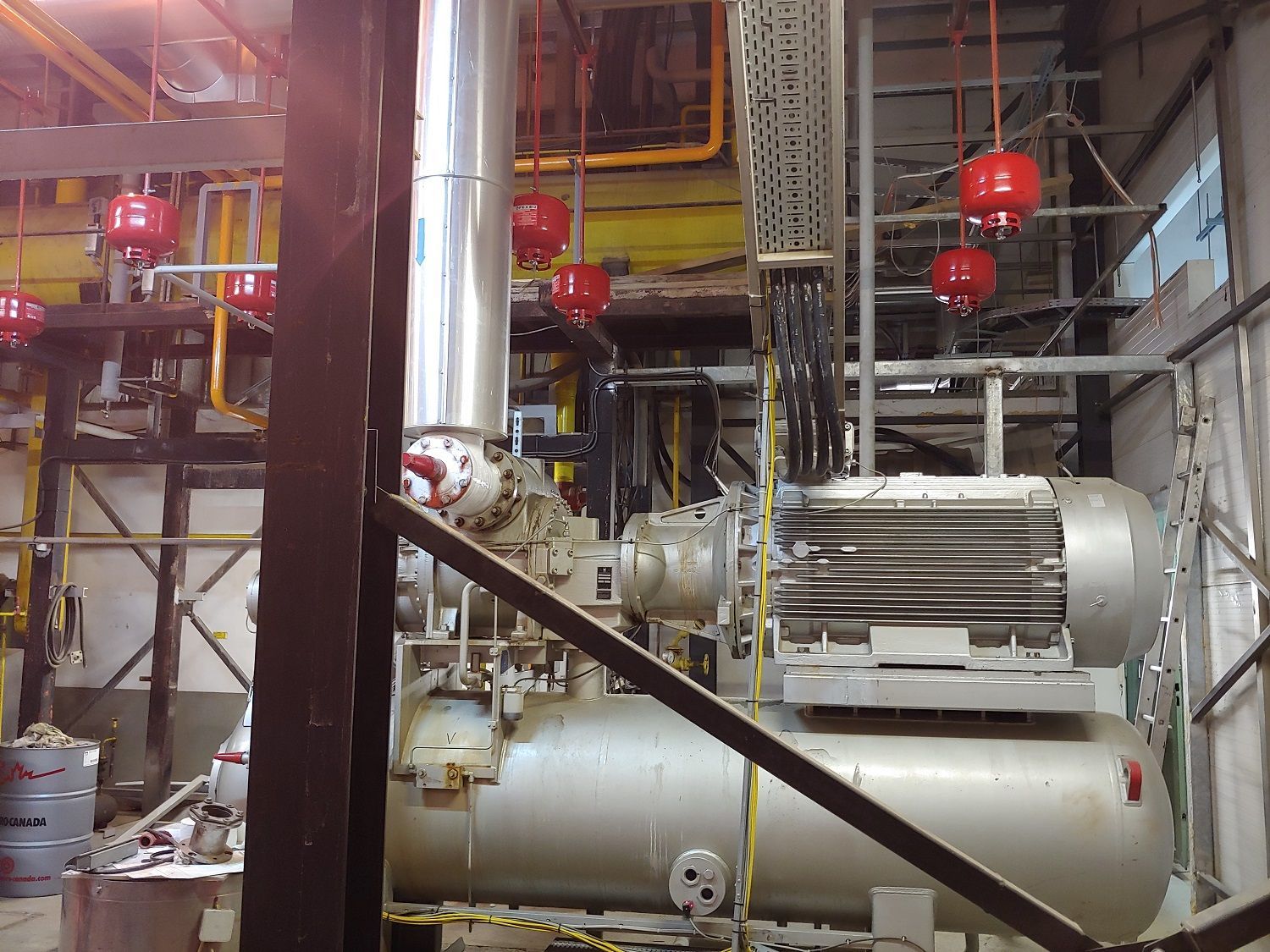 Industriële machines, mogelijk voor de productie, met rode brandveiligheidsbollen erboven.