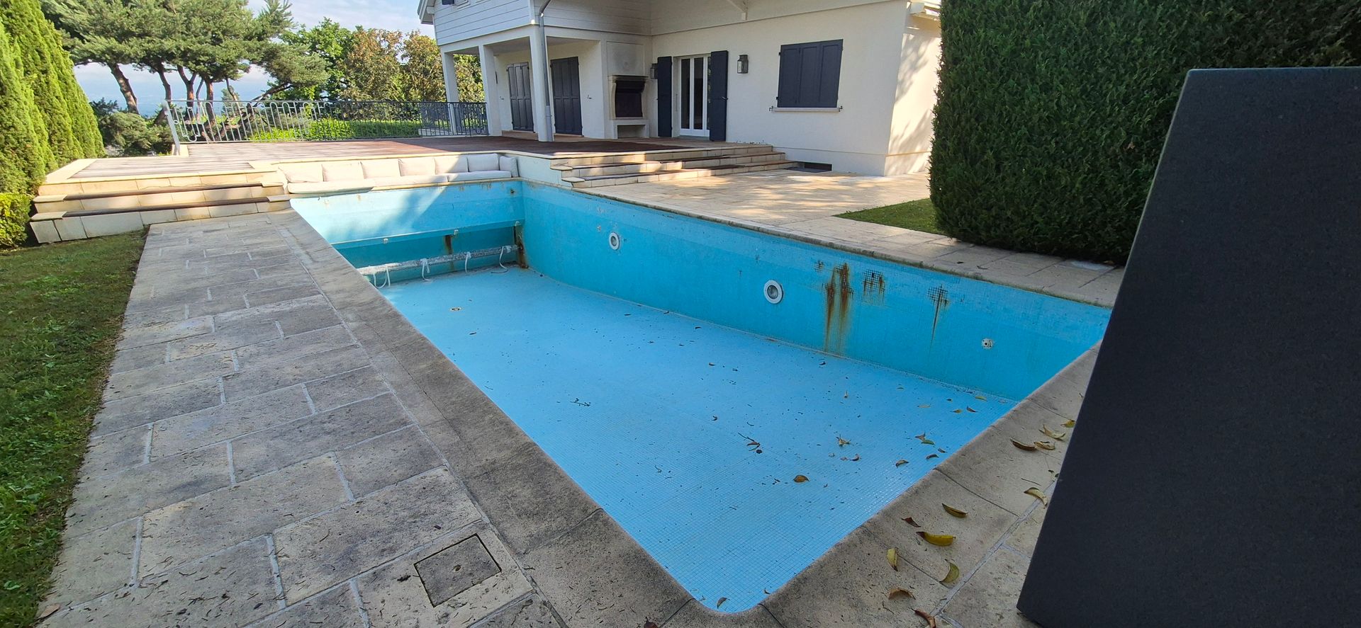 Une piscine vide devant une maison.