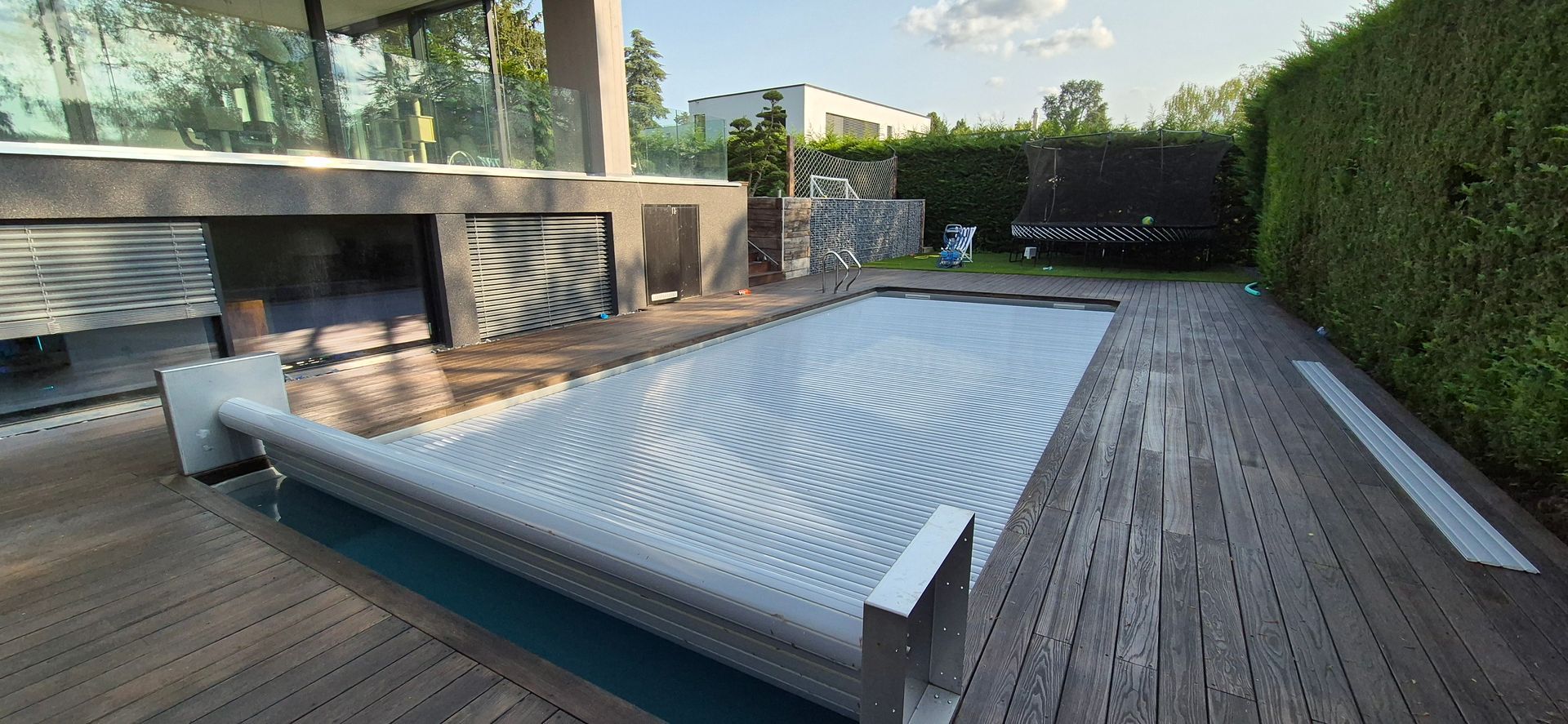 Une piscine avec une couverture et une maison en arrière-plan.