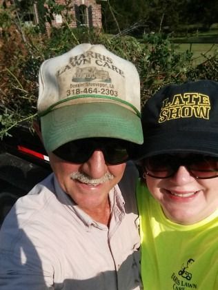 Two smiling people in sunglasses and hats posing outdoors in bright sunlight.