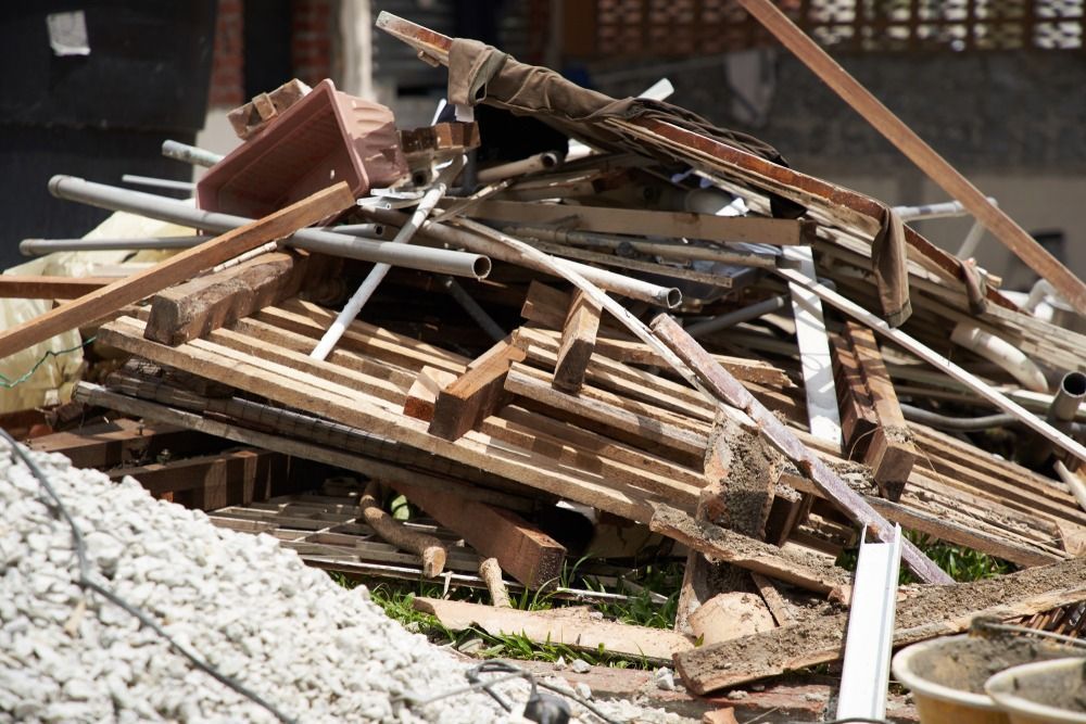 Pile of broken wooden debris and boards with some white rubble at a construction site
