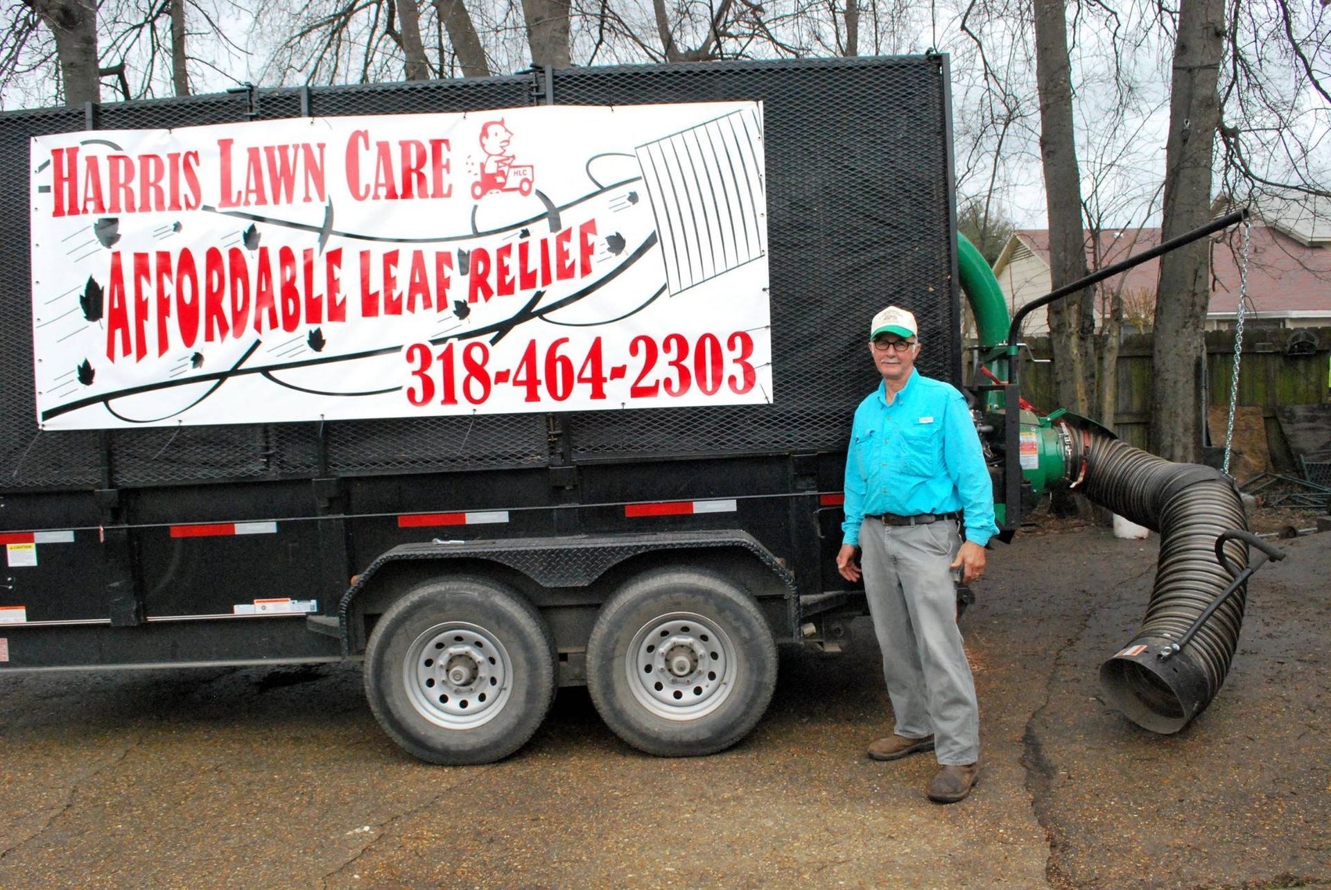 Lawn care trailer with “Affordable Leaf Relief” sign; worker in teal shirt stands beside a leaf blower.