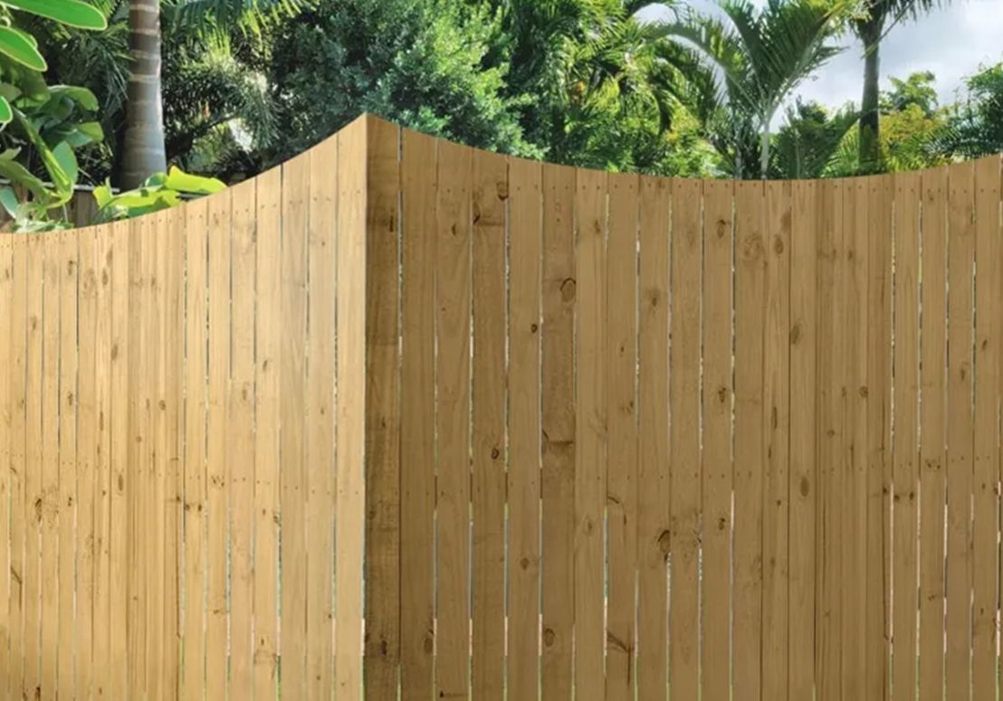 Tall wooden fence with greenery visible above it