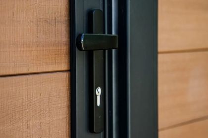 Close-up of a black door handle and lock on a wood-paneled door