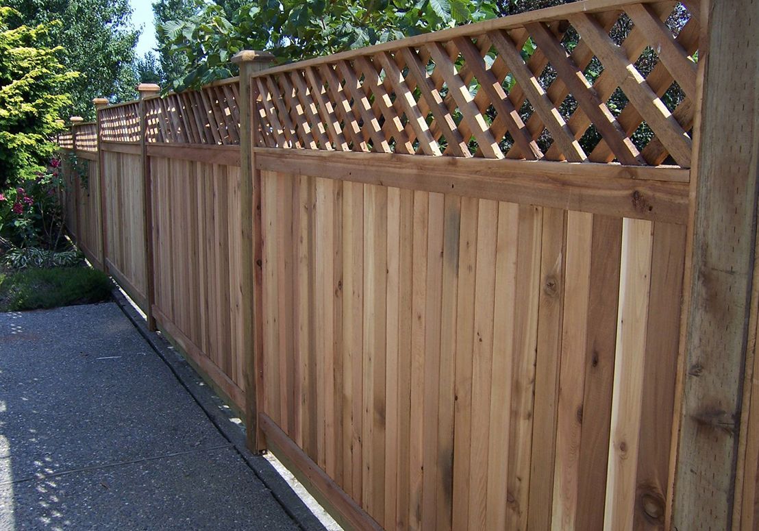 Wooden privacy fence with lattice top along a paved driveway