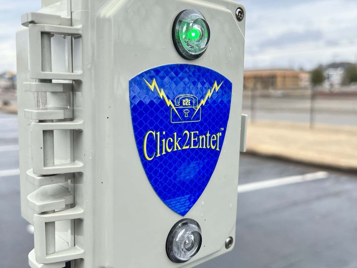 Close-up of a Click2Enter access control device with green indicator light on a post outdoors