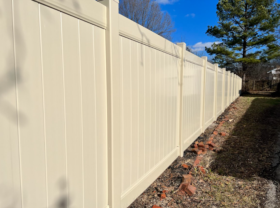 White vinyl fence along a gravel path on a sunny day