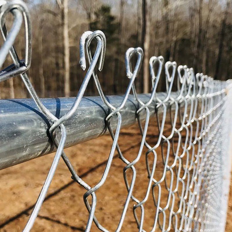 Close-up of a chain-link fence with silver wire along a metal rail outdoors