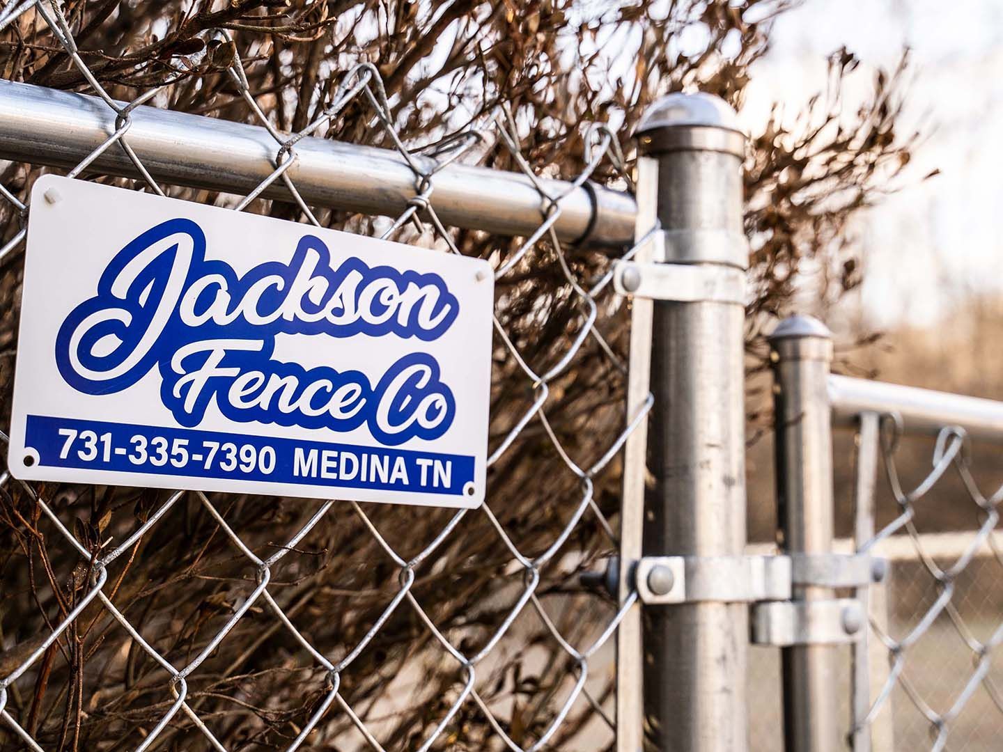 Jackson Fence Co. sign on chain-link fence with phone number and Medina, TN