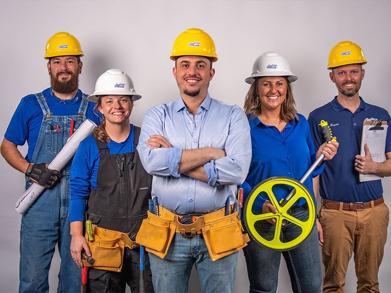 Five utility workers in hard hats with tools, standing together and smiling.