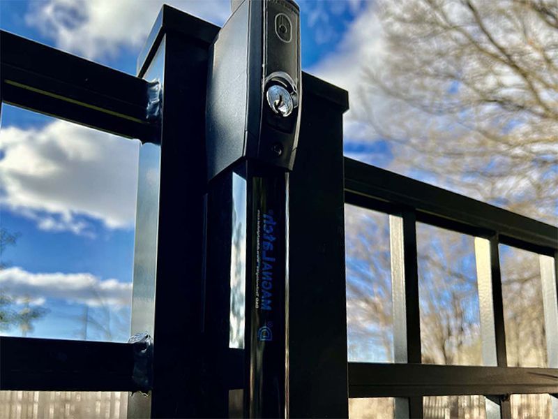 Black metal gate lock with blue sky and clouds behind it