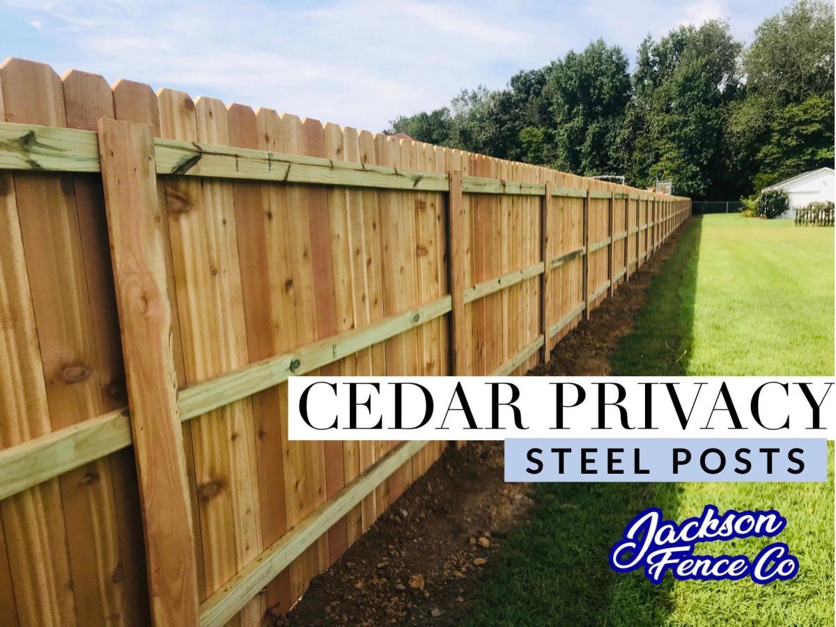 Cedar privacy fence with steel posts along a property line, with Jackson Fence logo overlay.