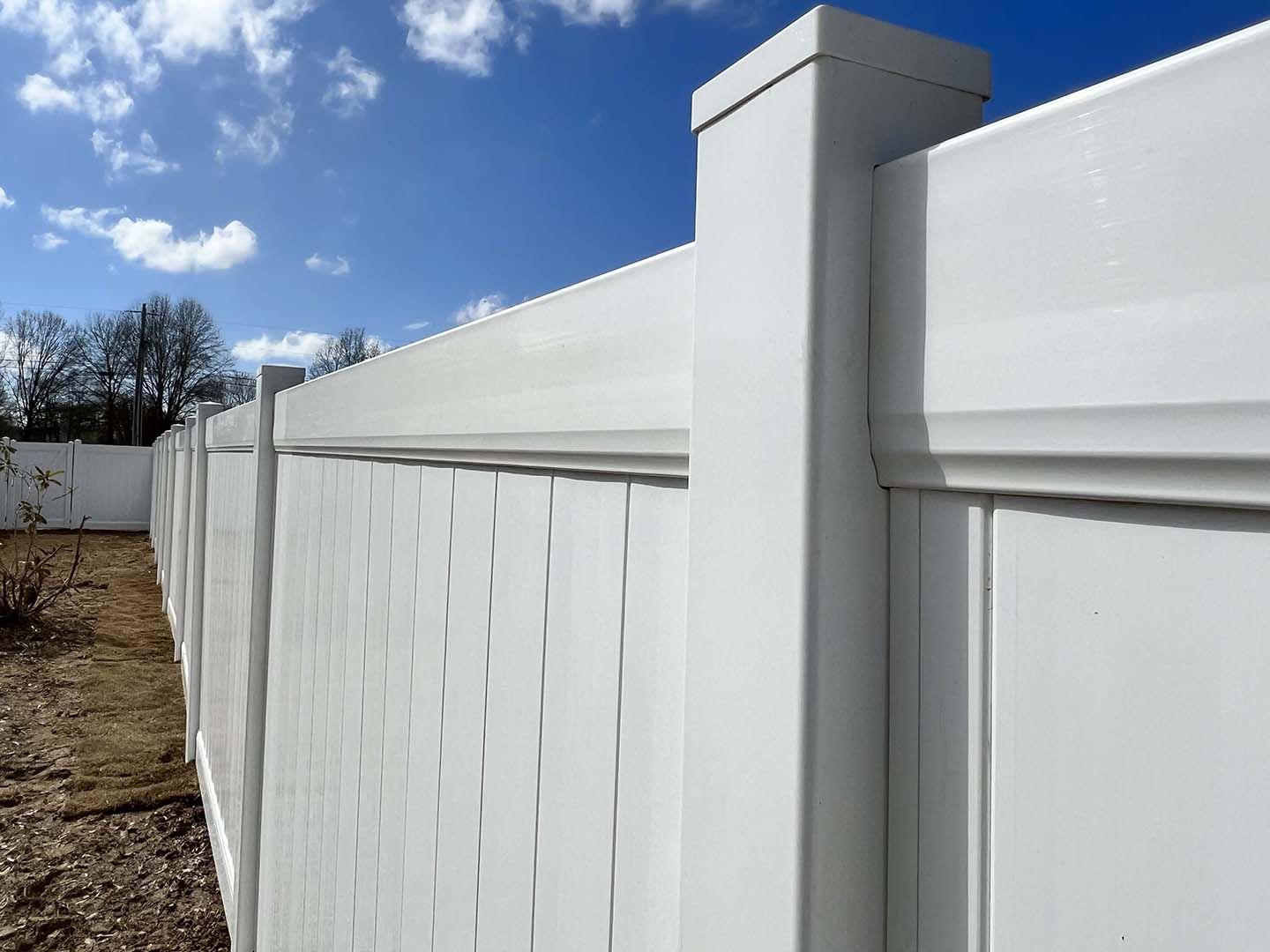 White vinyl privacy fence with square posts under a blue sky
