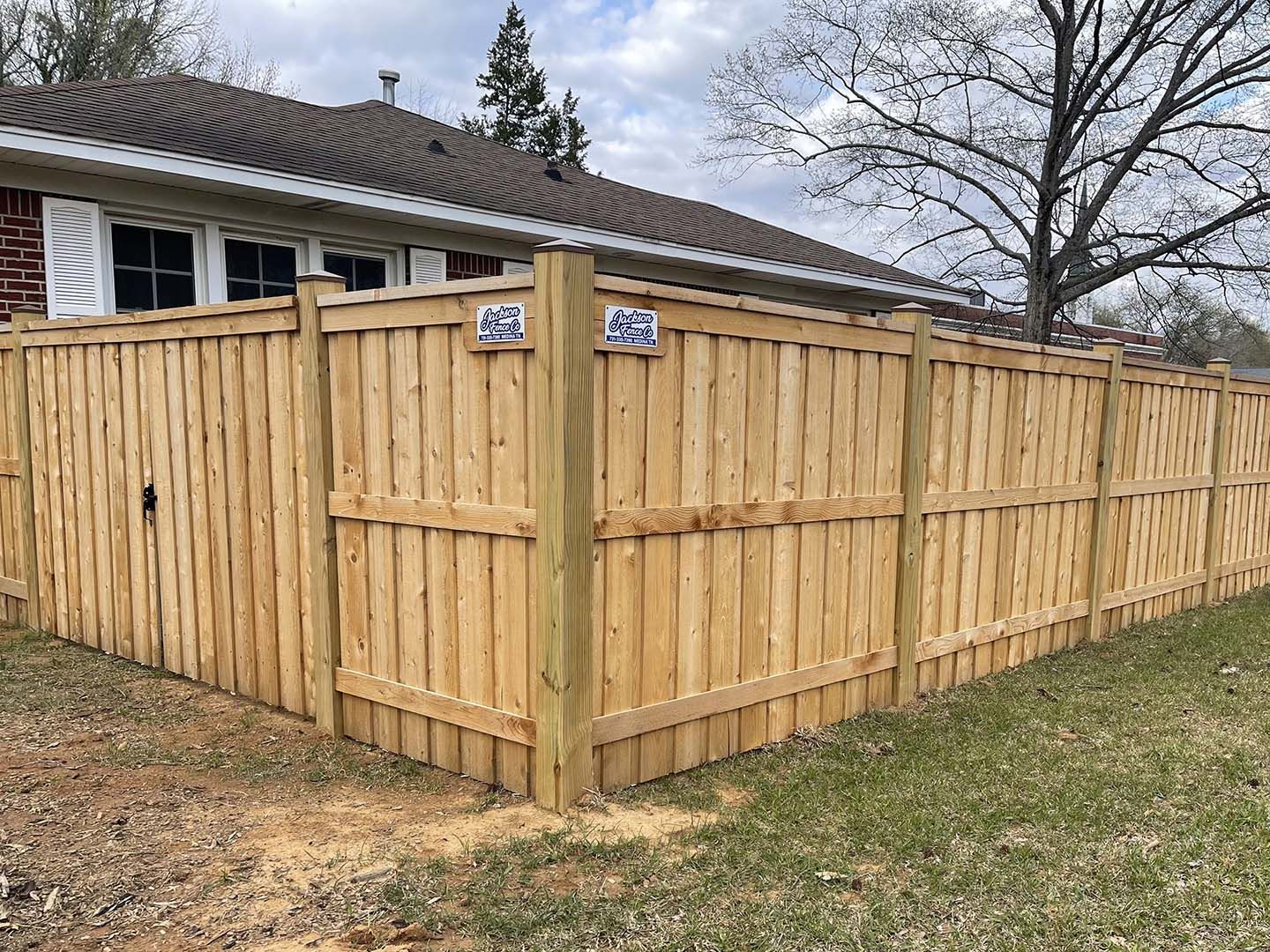 Wooden privacy fence enclosing a backyard beside a house, with blue address signs on the corner.