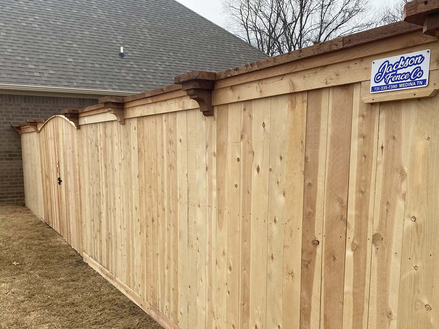 New wooden privacy fence beside a house, with a small sign near the top right.