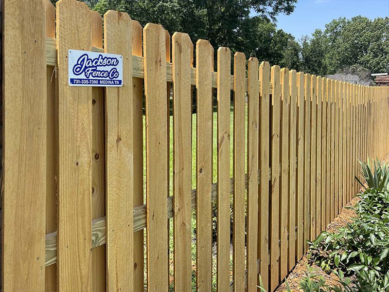 Wooden privacy fence with a blue sign in a sunny backyard