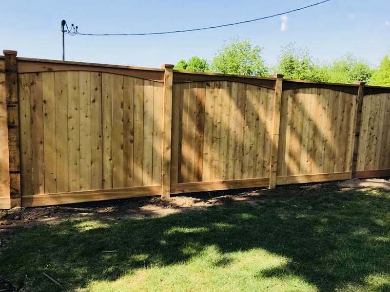 Wooden privacy fence in a grassy backyard under a clear blue sky