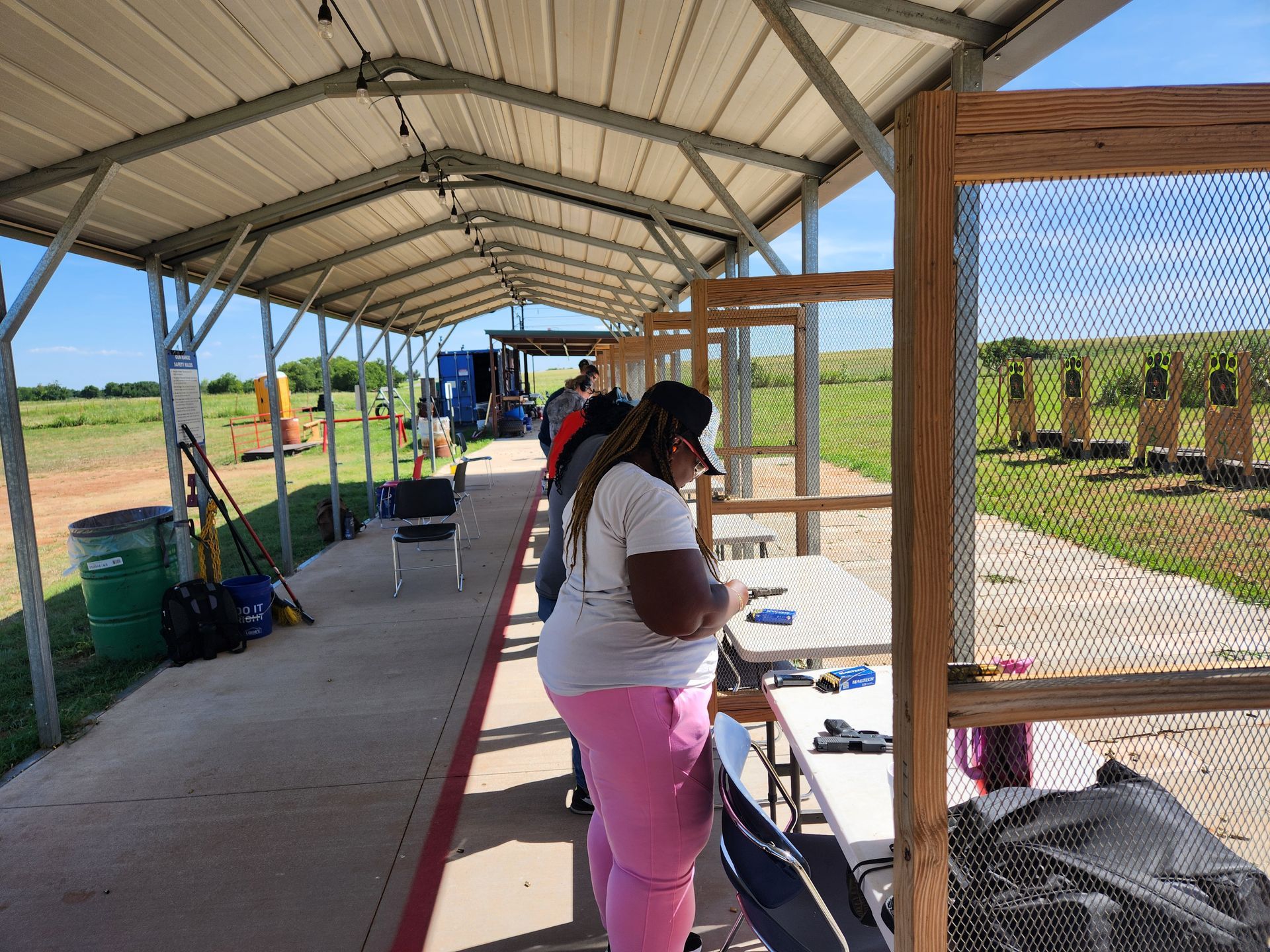 Hand holding a pistol aimed at a target in an indoor shooting range