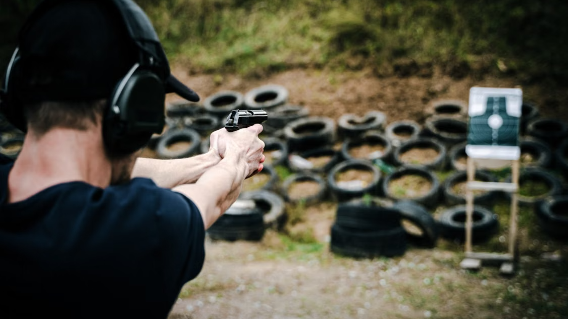 Hand holding a gun aimed at a target board in an indoor shooting range