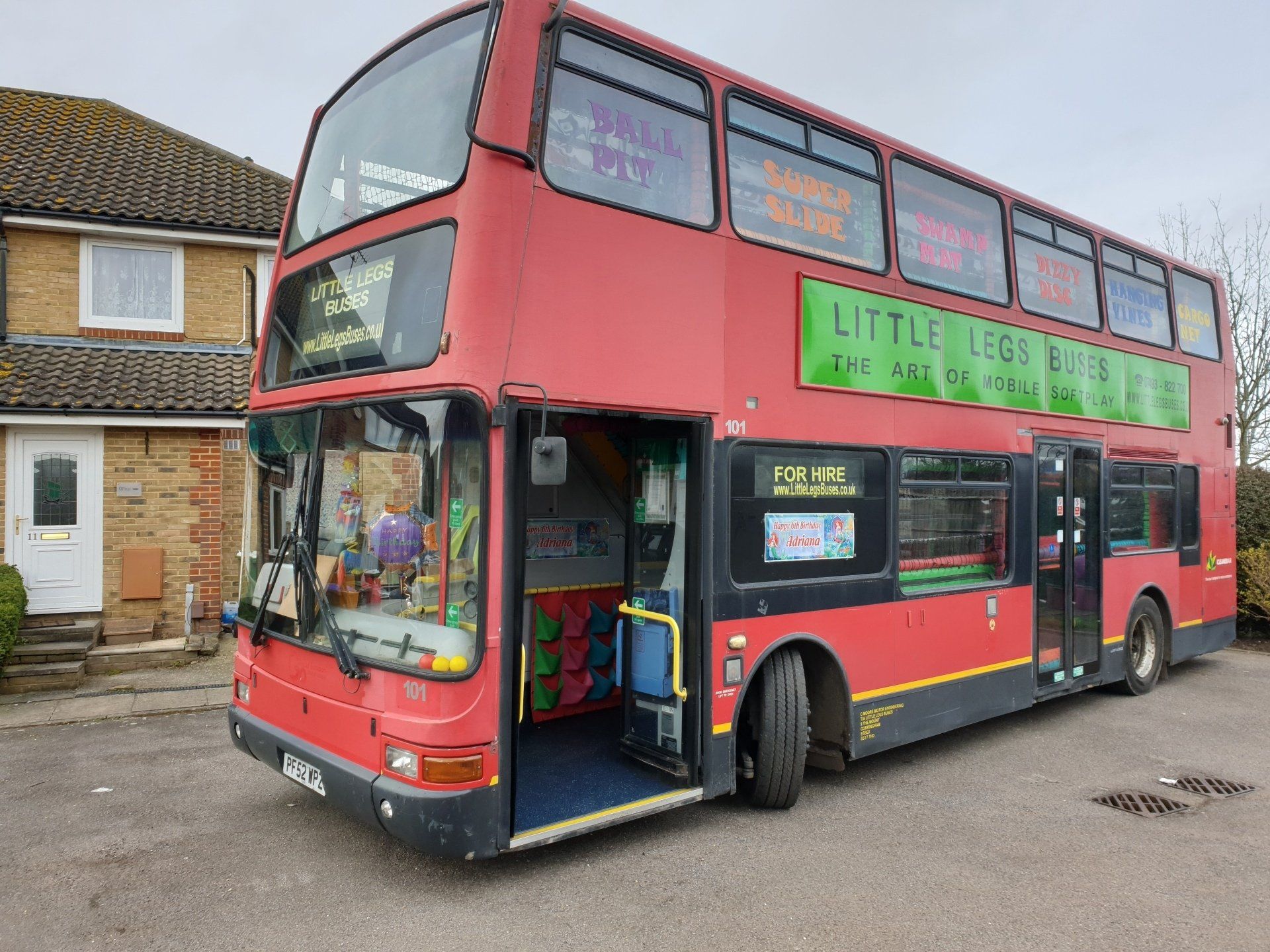 A red double decker bus is parked in front of a house
