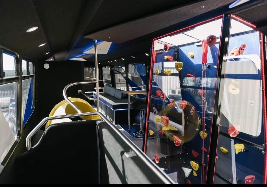 The inside of a bus with a climbing wall in the back