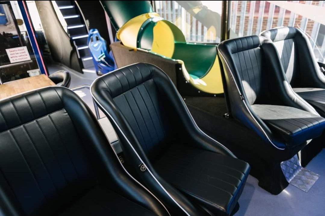 A row of black seats in a room with a slide in the background