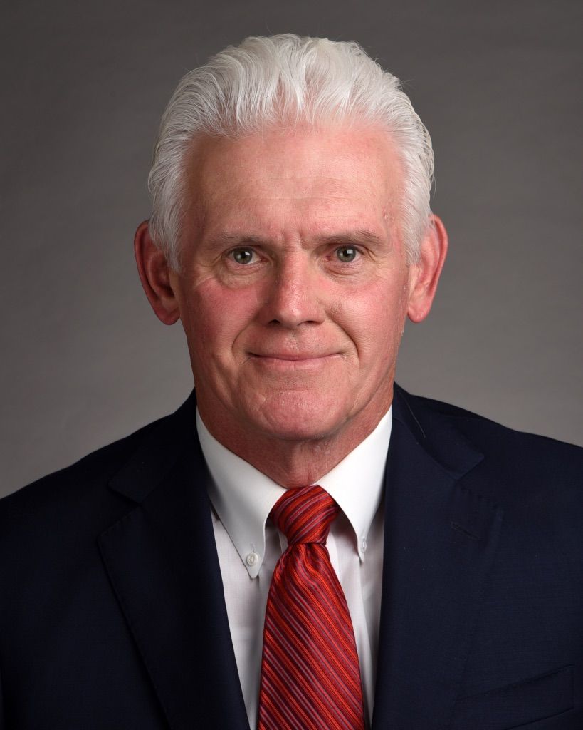 A man in a suit and tie is smiling for the camera