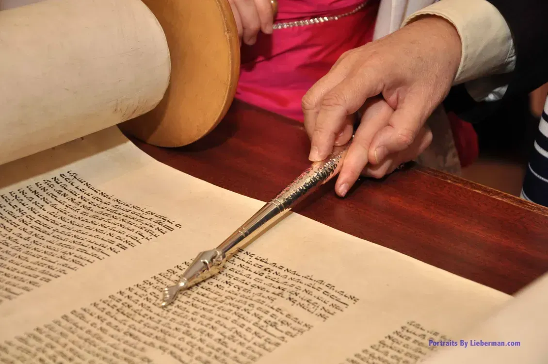 A person is reading a scroll of the torah