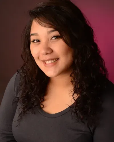 A woman with curly hair is smiling and wearing a black shirt