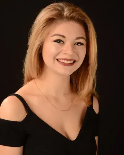A woman in a black dress is smiling for the camera.